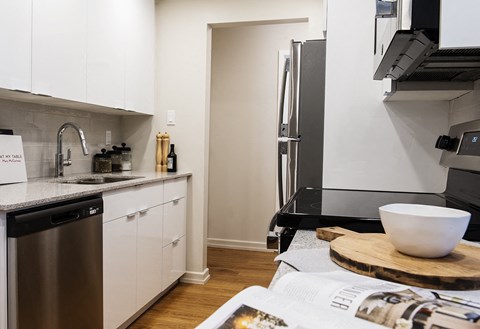 a kitchen with white cabinets and a black counter top and a stainless steel refrigerator